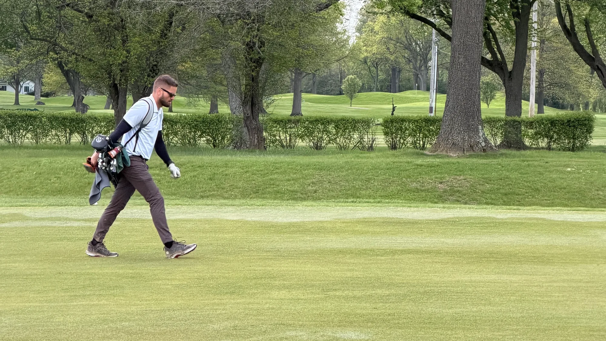 Colin Coughlin walking a fairway with his carry bag on a tree-lined Northeast Ohio course